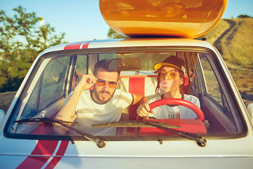 Image showing Laughing romantic couple sitting in car while out on a road trip at summer day