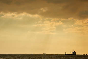 Image showing Sunset over large body of water with rays of light coming through clouds