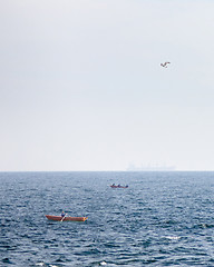 Image showing View of fishing boats on a background of blue open sea and a tanker blurred on the horizon