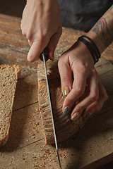 Image showing Female hands cut freshly baked bread