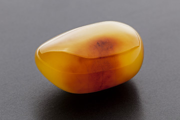 Image showing Natural amber. A piece of yellow opaque natural amber on dark grey background.