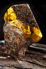 Image showing Natural amber stone. A piece of dirty amber with transparent yellow layer on piece of stoned wood.