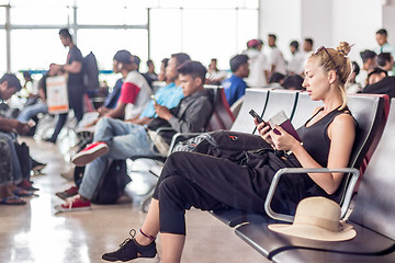 Image showing Female traveler using her cell phone while waiting to board a plane at departure gates at asian airport terminal.