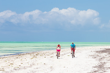 Image showing Two caucasian tourist cycling on perfect tropical white sandy Paje beach, Zanzibar, Tanzania.