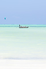 Image showing fishing boat and a kite surfer on picture perfect white sandy beach with turquoise blue sea, Paje, Zanzibar, Tanzania.