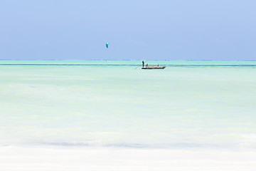 Image showing fishing boat and a kite surfer on picture perfect white sandy beach with turquoise blue sea, Paje, Zanzibar, Tanzania.