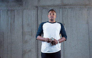 Image showing black business man displaying a spread of american dollar cash m