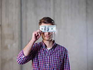 Image showing business man holding american dollars banknote over the eyes