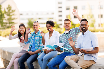 Image showing students with notebook waving hands outdoors