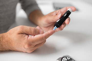 Image showing senior man with glucometer checking blood sugar