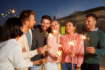 Image showing happy friends with sparklers at rooftop party