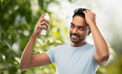 Image showing man applying hair spray over natural background