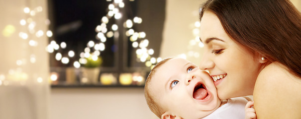 Image showing close up of mother with baby over christmas lights