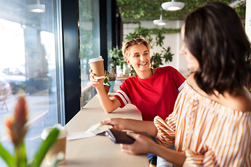 Image showing female friends paying for coffee at cafe