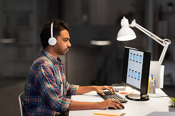 Image showing creative man in headphones working at night office