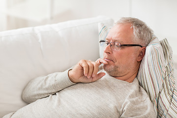 Image showing senior man  lying on sofa and thinking at home