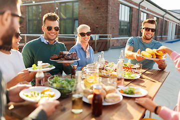 Image showing happy friends eating at barbecue party on rooftop