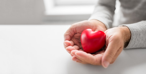 Image showing cupped senior man hands with red heart shape