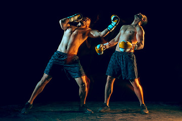 Image showing Male boxer boxing in a dark studio