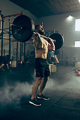 Image showing Fit young man lifting barbells working out in a gym