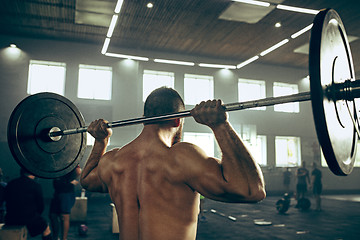 Image showing Fit young man lifting barbells working out in a gym