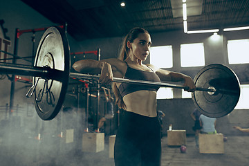 Image showing Fit young woman lifting barbells working out in a gym