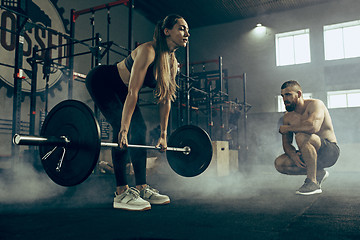 Image showing Fit young woman lifting barbells working out in a gym