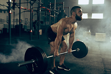 Image showing Fit young man lifting barbells working out in a gym