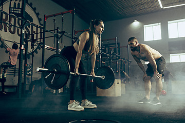 Image showing Fit young woman lifting barbells working out in a gym