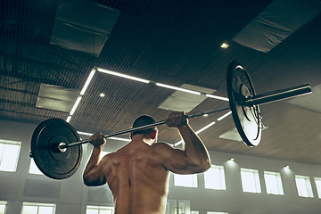 Image showing Fit young man lifting barbells working out in a gym