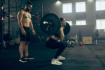 Image showing Fit young woman lifting barbells working out in a gym