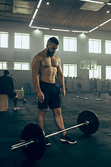 Image showing Fit young man lifting barbells working out in a gym