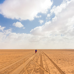 Image showing Solitary masai worrior walking along salt lake desert road in Kenya, Amboseli Natural Park, Africa