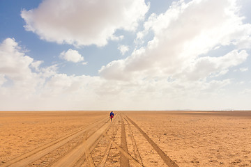 Image showing Solitary masai worrior walking along salt lake desert road in Kenya, Amboseli Natural Park, Africa