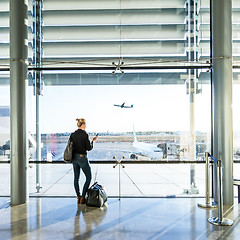 Image showing Young woman waiting at airport, looking through the gate window.