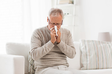 Image showing sick senior man with paper wipe blowing his nose