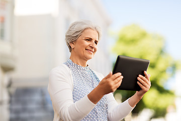 Image showing smiling senior woman with tablet pc on city street