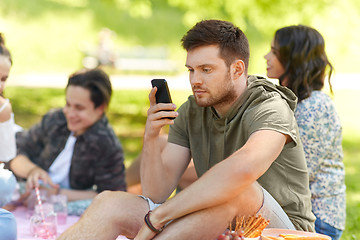 Image showing man using smartphone at picnic with friends