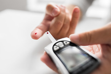 Image showing senior man with glucometer checking blood sugar