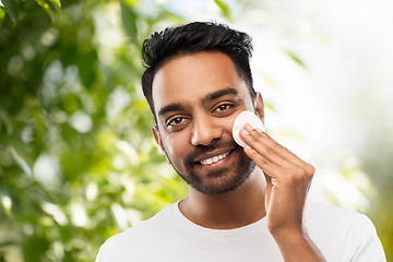 Image showing smiling indian man cleaning face with cotton pad