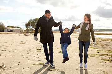 Image showing happy family walking along autumn beach