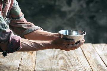 Image showing Male beggar hands seeking money on the wooden floor at public path way