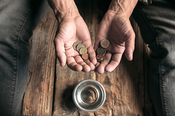 Image showing Male beggar hands seeking money on the wooden floor at public path way