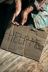 Image showing Male beggar hands seeking money on the wooden floor at public path way