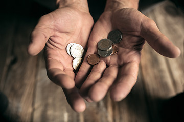 Image showing Male beggar hands seeking money on the wooden floor at public path way