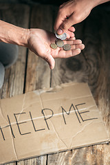 Image showing Male beggar hands seeking money on the wooden floor at public path way