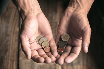 Image showing Male beggar hands seeking money on the wooden floor at public path way