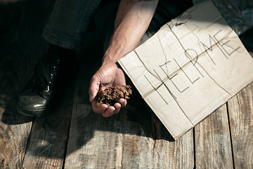 Image showing Male beggar hands seeking money on the wooden floor at public path way