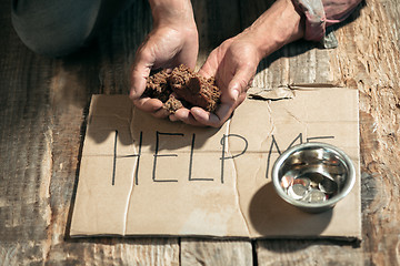 Image showing Male beggar hands seeking money on the wooden floor at public path way