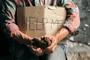 Image showing Male beggar hands seeking money on the wooden floor at public path way